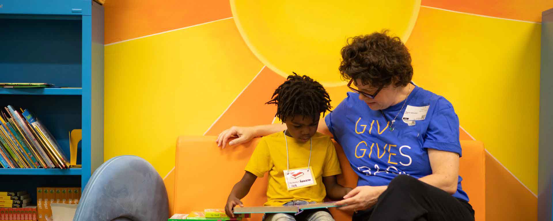 Woman in a Liberty Cares t-shirt reading to a student.